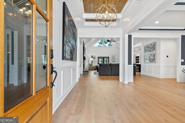 foyer entrance featuring crown molding, light hardwood / wood-style flooring, and ceiling fan with notable chandelier