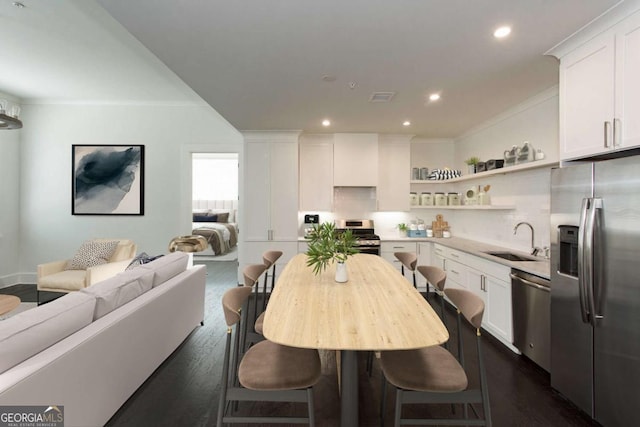 kitchen with sink, crown molding, appliances with stainless steel finishes, white cabinetry, and dark hardwood / wood-style floors