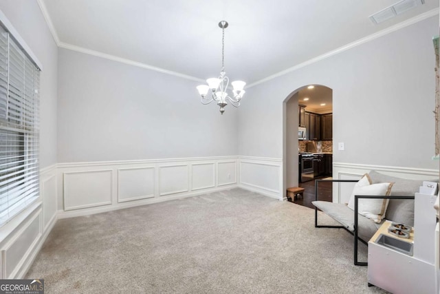 unfurnished room featuring crown molding, an inviting chandelier, and carpet