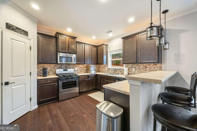 kitchen with pendant lighting, sink, a breakfast bar, stainless steel appliances, and kitchen peninsula