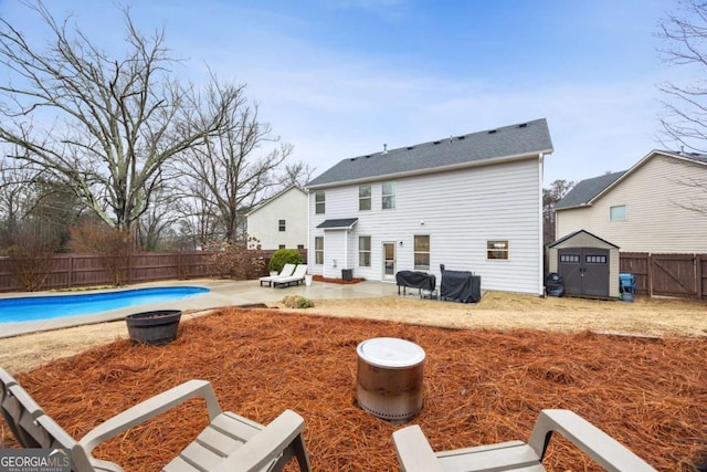 back of property featuring a fenced in pool, a patio, and a shed