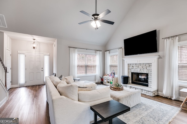 living room with hardwood / wood-style flooring, a stone fireplace, high vaulted ceiling, and ceiling fan