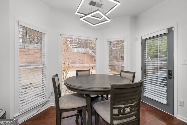 dining space with ornamental molding, dark wood finished floors, and baseboards