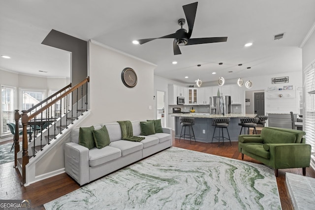 living room featuring dark wood-style floors, ornamental molding, stairway, and visible vents