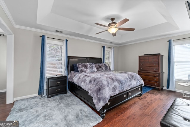 bedroom featuring ornamental molding, wood finished floors, a raised ceiling, and visible vents