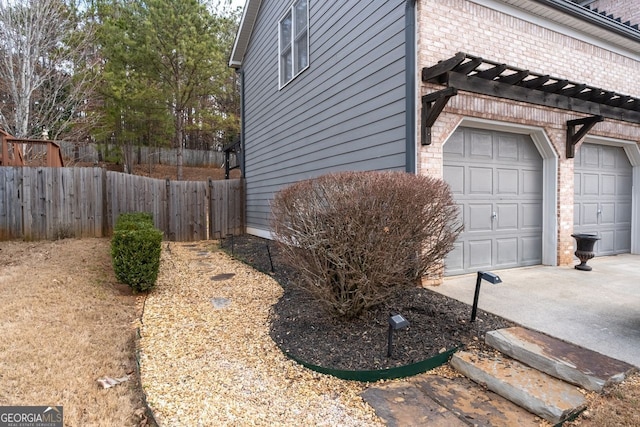 view of side of home featuring a garage, brick siding, fence, and driveway