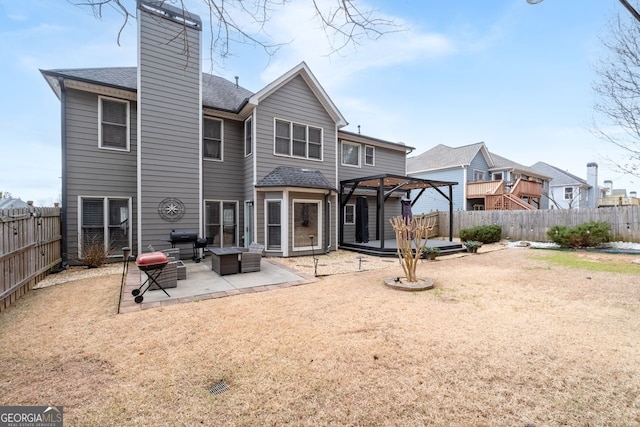 rear view of house with a patio, a chimney, a fenced backyard, and roof with shingles