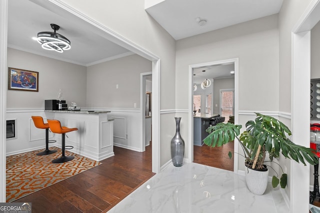 bar with ornamental molding, baseboards, and wood finished floors