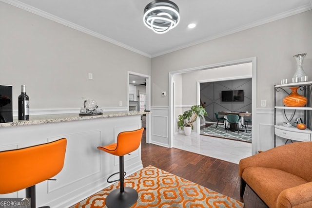 kitchen with dark wood-style floors, ornamental molding, a decorative wall, and a wainscoted wall