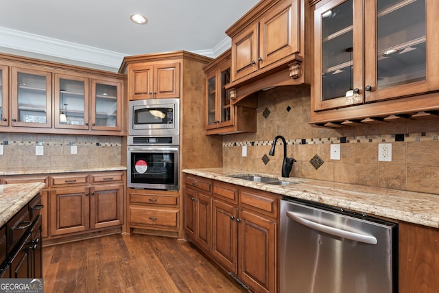 kitchen with sink, dark wood-type flooring, appliances with stainless steel finishes, ornamental molding, and light stone countertops