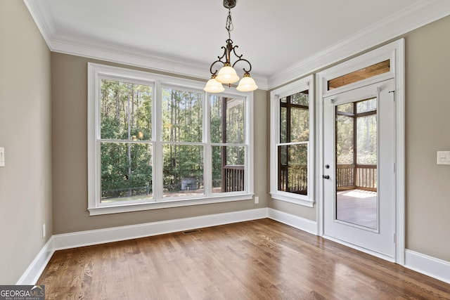 interior space with a notable chandelier, hardwood / wood-style flooring, and ornamental molding