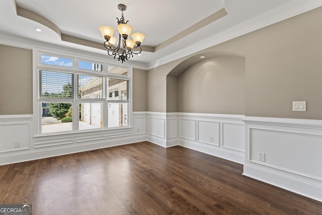 spare room with dark hardwood / wood-style flooring, ornamental molding, a raised ceiling, and a chandelier