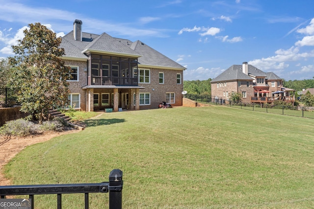 rear view of property featuring a sunroom and a yard