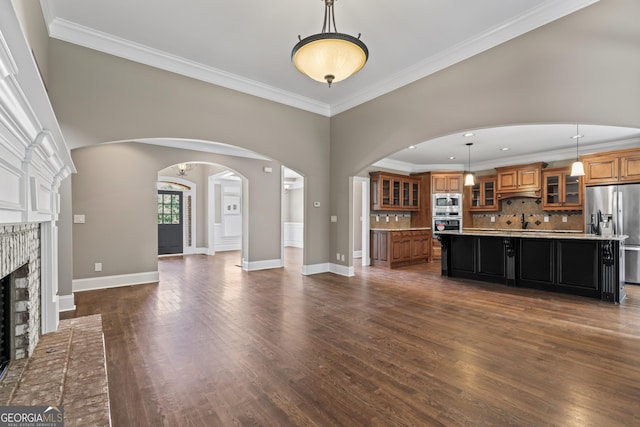 unfurnished living room with a brick fireplace, dark wood-type flooring, and ornamental molding