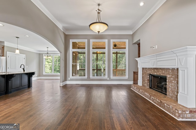 unfurnished living room with crown molding, dark hardwood / wood-style floors, sink, and a fireplace