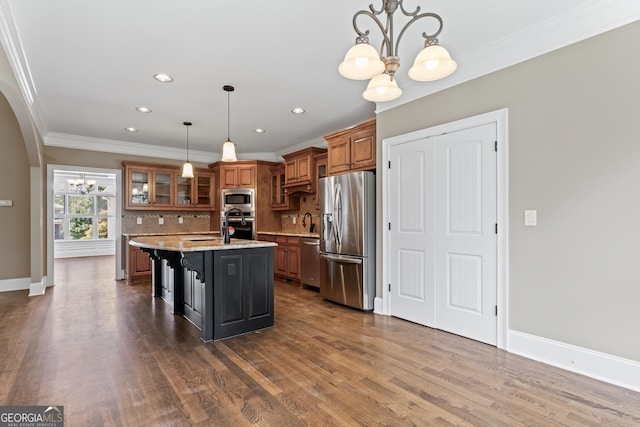 kitchen with an island with sink, a breakfast bar area, a chandelier, stainless steel appliances, and light stone countertops