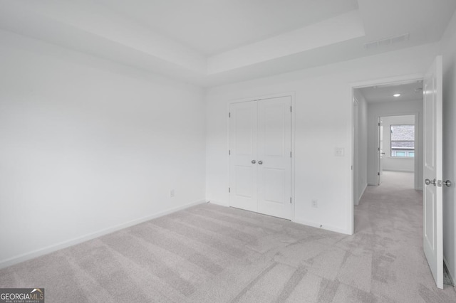 3812 Thatcher Dr SW, Marietta, GA 30008 - unfurnished bedroom featuring a tray ceiling, visible vents, baseboards, light colored carpet, and a closet