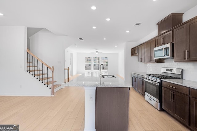 3812 Thatcher Dr SW, Marietta, GA 30008 - kitchen with light wood finished floors, a kitchen island with sink, a sink, visible vents, and appliances with stainless steel finishes