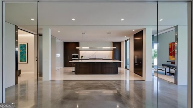 kitchen with hanging light fixtures, an island with sink, and dark brown cabinetry