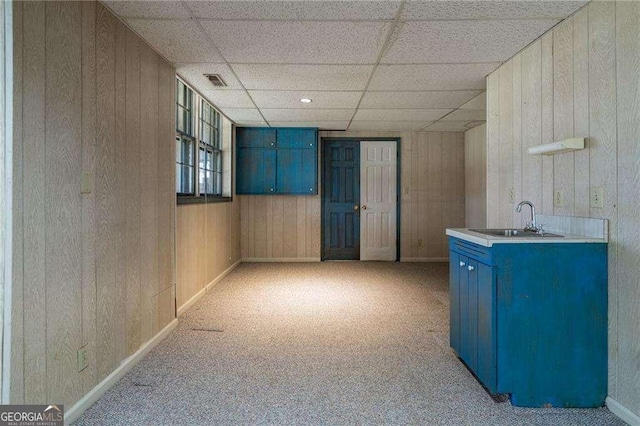 interior space with a paneled ceiling, wooden walls, and sink