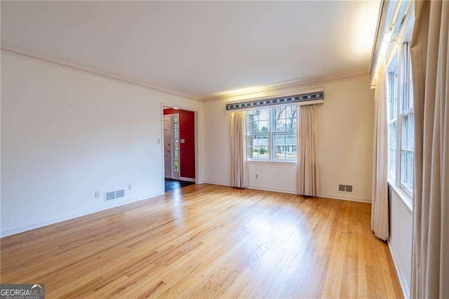 empty room with ornamental molding and light hardwood / wood-style floors