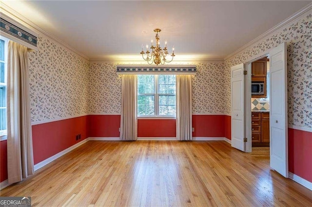 unfurnished dining area with ornamental molding, a notable chandelier, and light hardwood / wood-style flooring