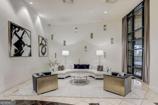 living room featuring a towering ceiling, light tile patterned floors, and a wall of windows