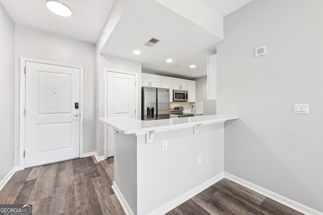 3040 Peachtree Rd NW Unit 613, Atlanta, GA 30305 - kitchen featuring stainless steel appliances, a peninsula, a breakfast bar, dark wood-style floors, and white cabinetry