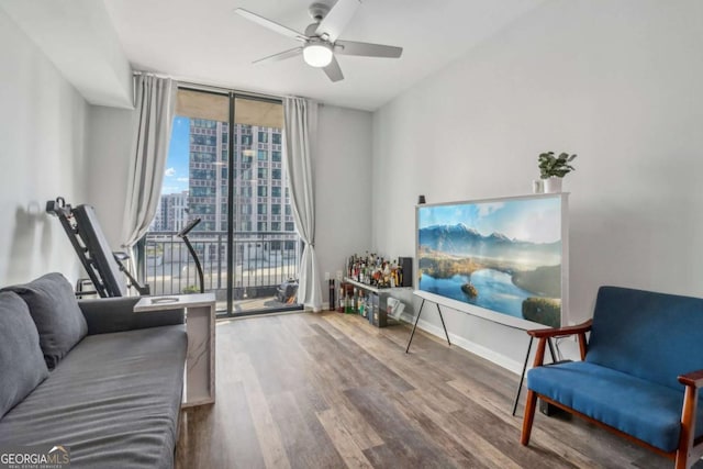 sitting room featuring hardwood / wood-style flooring, a wall of windows, and ceiling fan