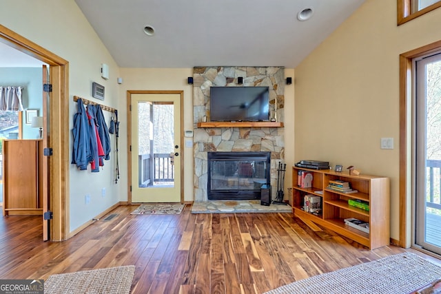 living area featuring a fireplace, baseboards, vaulted ceiling, and wood finished floors