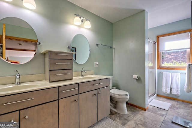 bathroom with toilet, a stall shower, double vanity, and a sink