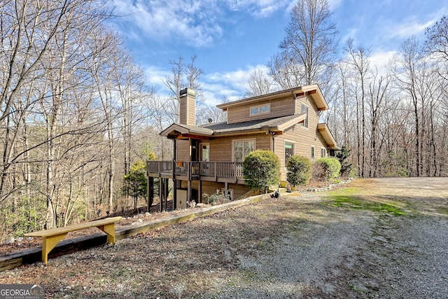 rear view of house with a chimney and a wooden deck