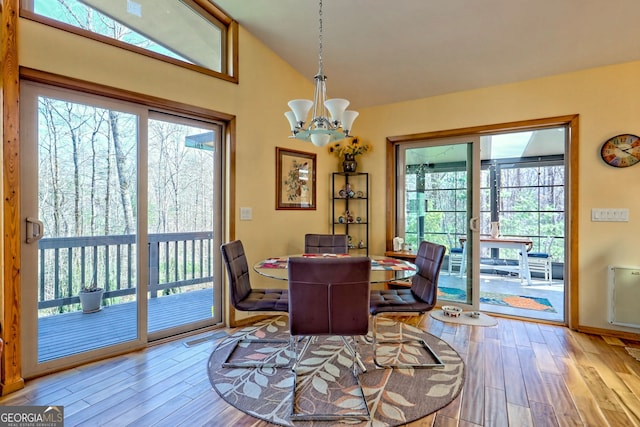 dining area featuring a chandelier, wood finished floors, and lofted ceiling