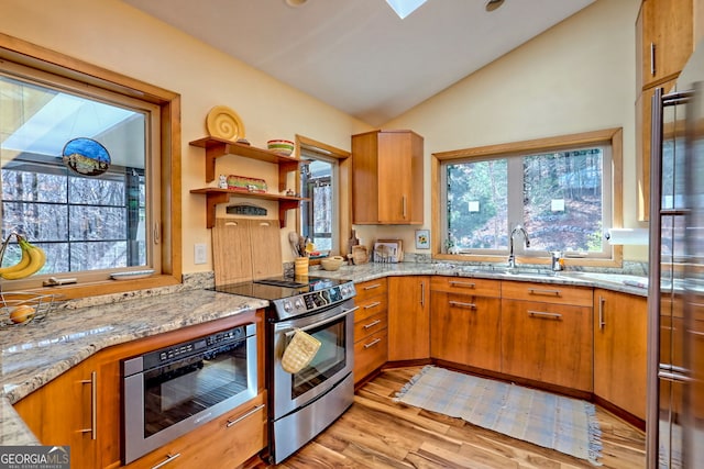 kitchen featuring light stone counters, electric range, a sink, vaulted ceiling, and light wood finished floors