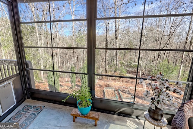 unfurnished sunroom featuring a healthy amount of sunlight and a wooded view