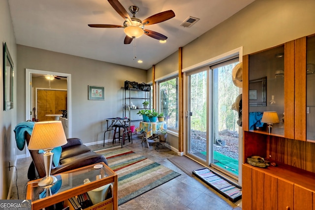 living area featuring baseboards, visible vents, and a ceiling fan