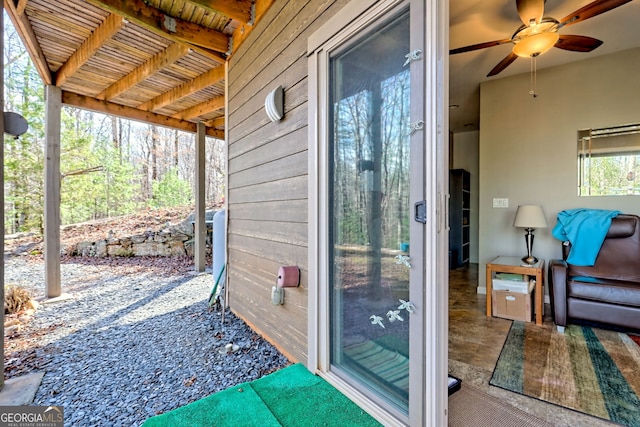 doorway to outside featuring wood walls and a ceiling fan