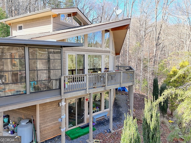 back of house featuring a sunroom and a wooden deck