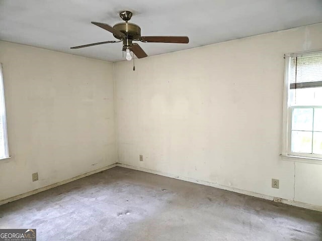 spare room featuring a healthy amount of sunlight, concrete floors, and ceiling fan