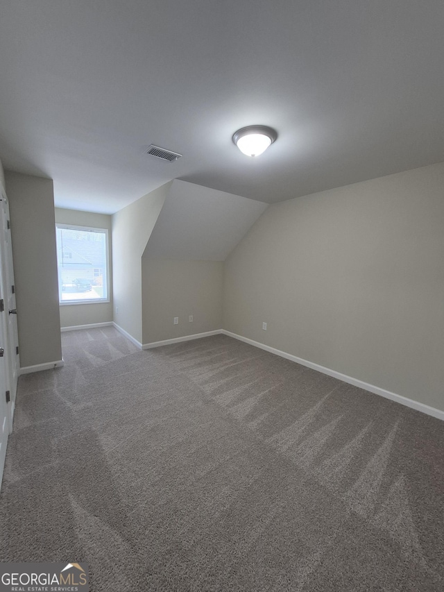 additional living space featuring visible vents, carpet floors, baseboards, and vaulted ceiling