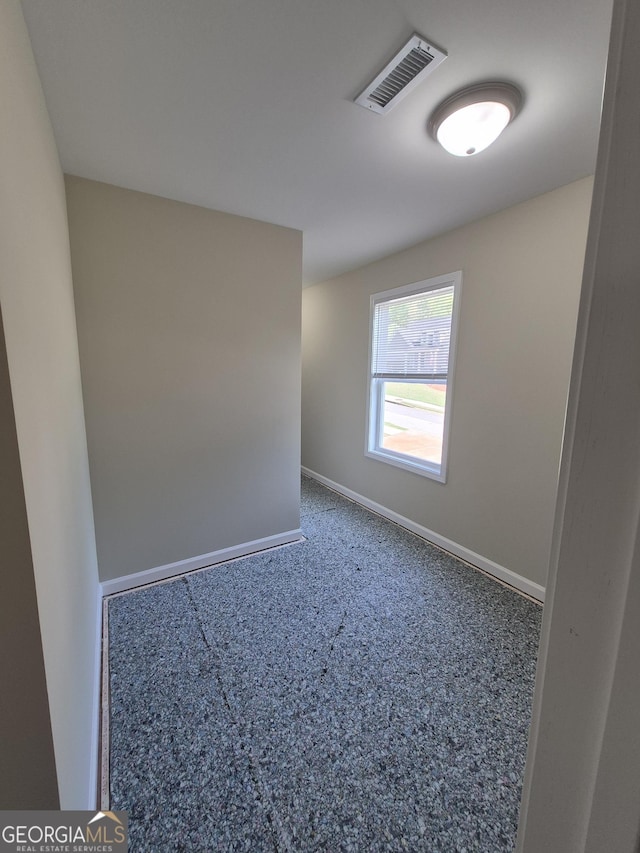 carpeted empty room featuring baseboards and visible vents