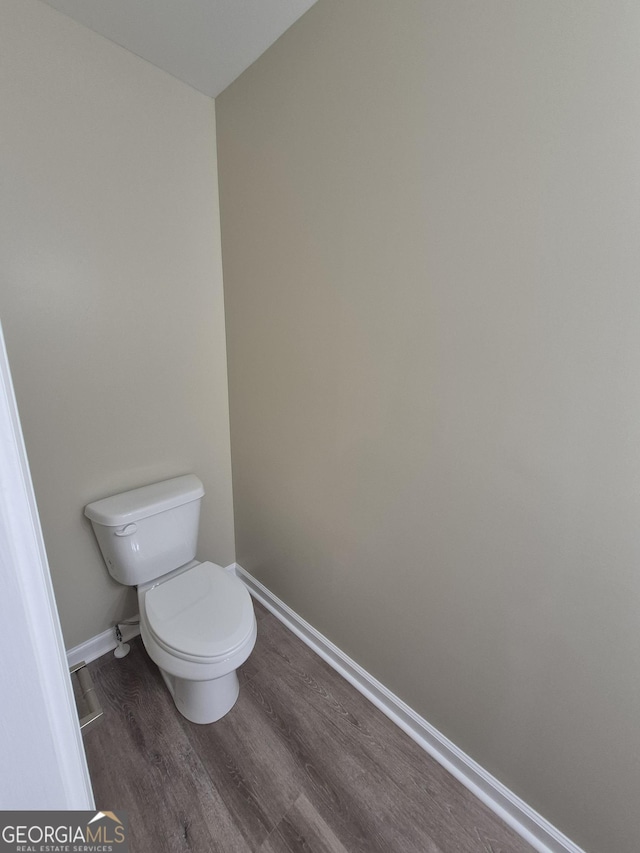 bathroom featuring toilet, wood finished floors, and baseboards