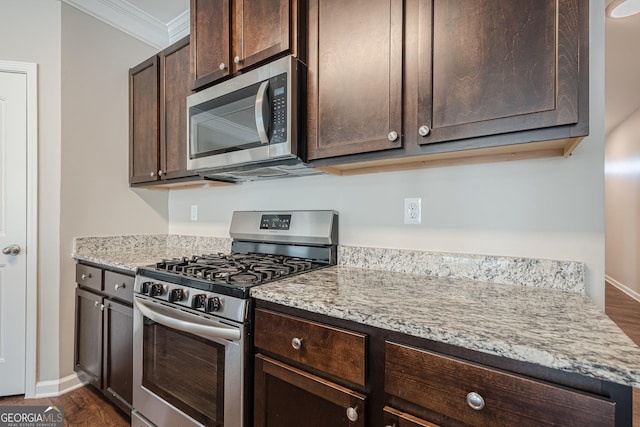 kitchen with dark brown cabinets, dark wood-style floors, appliances with stainless steel finishes, and ornamental molding