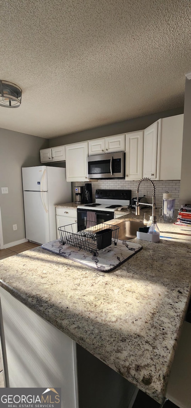 kitchen featuring white cabinetry, electric range oven, white refrigerator, kitchen peninsula, and decorative backsplash