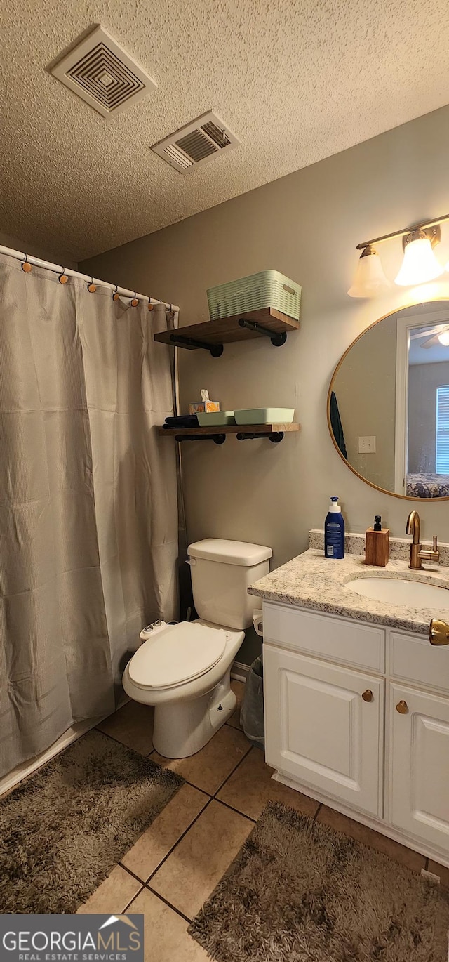 bathroom featuring vanity, toilet, tile patterned flooring, and a textured ceiling