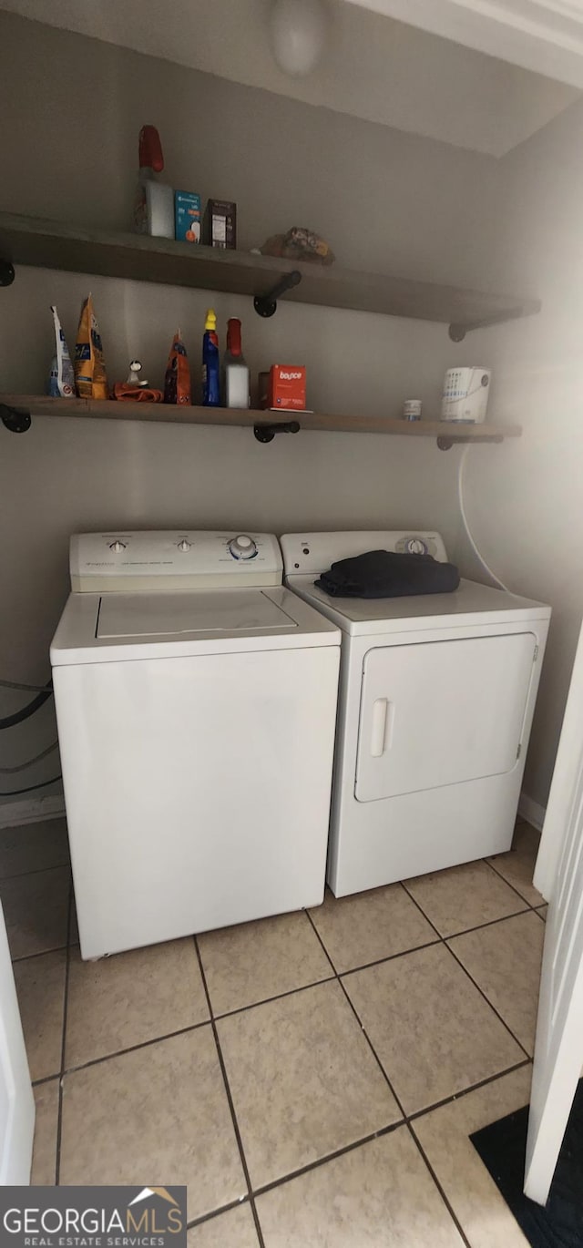 clothes washing area with washing machine and dryer and light tile patterned flooring