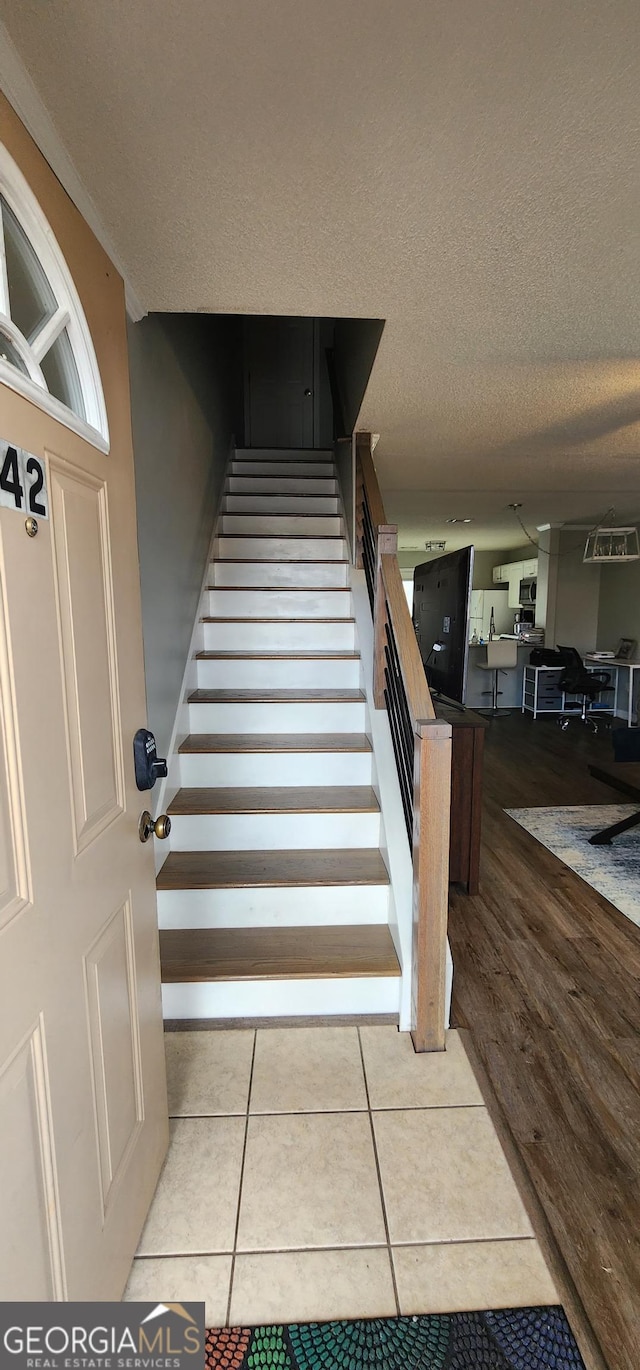 stairs with hardwood / wood-style flooring and a textured ceiling