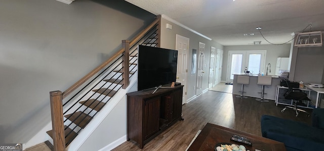 living room featuring hardwood / wood-style flooring, crown molding, and french doors