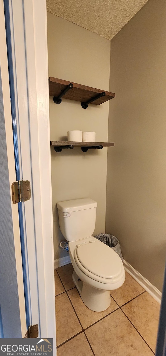 bathroom with tile patterned flooring, a textured ceiling, and toilet