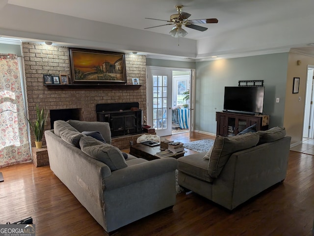 living room featuring dark hardwood / wood-style flooring, ceiling fan, crown molding, and a fireplace